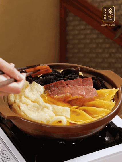 砂锅底部铺上娃娃菜，顺次摆上肉皮、蛋饺、黑木耳、火腿